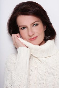 Middle-aged woman rubbing cowl neck of sweater against cheek